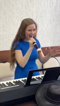 Caucasian woman singing into microphone. 