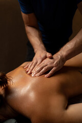 Close-up of a professional therapist performing a relaxing back massage in a spa setting, applying oil and pressure to relieve muscle tension and promote relaxation and wellbeing.