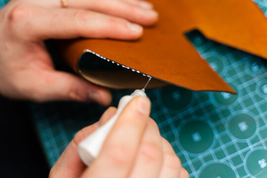 Gluing leather edges for stitching and lasting products. Leather glue application secures edges before sewing. Applying glue to leather edges ensures strong bonding before stitching.