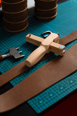 Leatherworking setup featuring tools, buckle, and leather strips laid out neatly on a mat, ready for belt making. Leathercraft tools and belt-making preparation.