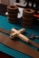 Leatherworking setup featuring tools, buckle, and leather strips laid out neatly on a mat, ready for belt making. Leathercraft tools and belt-making preparation.