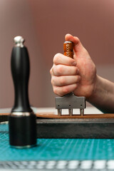 Crafting belt holes with punch tool on leather strap. Punching and detailing leather belt holes. Artisan punching holes into a leather strap for a handmade belt on a green cutting mat.