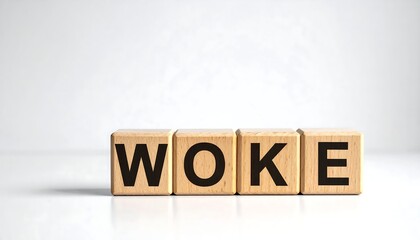 Four wooden blocks spell out "WOKE" on a white reflective surface against a blurry, bright background
