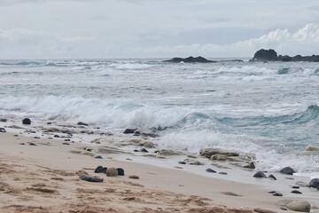 Peaceful Beach Scene With Waves Crashing On Pebble Shore Under Overcast Sky