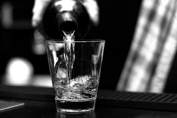 Black and white photo of a drink being poured into a glass at a bar—ideal for cocktail menus, upscale brochures, holiday drink ads, or elegant alcohol-focused marketing campaigns.