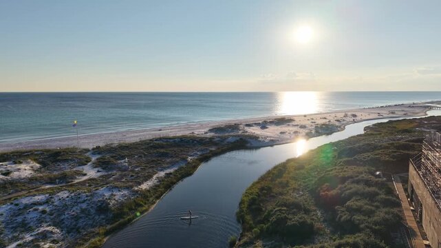 Drone orbit over coastal dunes and shoreline in gulf bay channel with beauty sun reflections, 30A, Florida, USA