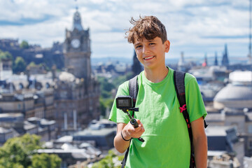 Teenage boy explorer film Edinburgh sights on a sunny hillside