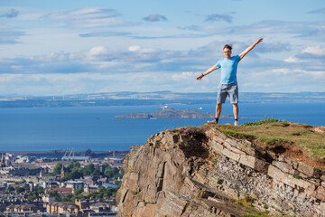 Explorer on cliff top, enjoying stunning ocean vista of Edinburg