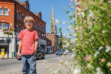 Boy smiles on a sunny street, flowers bloom nearby Farnham, UK