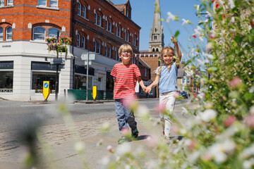 Bright day stroll with kids holding hands in town Farnham, UK