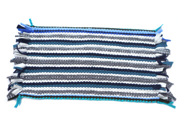 Handwoven fabric mat made from colorful recycled textile strips in shades of blue, gray, and white. Eco-friendly handmade craft showcasing traditional weaving technique and sustainable home decor