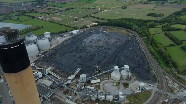 Aerial view of Drax Power Station, where the contrast of the dark ash pond against the lush green fields creates a stark visual statement, Selby, England, United Kingdom.