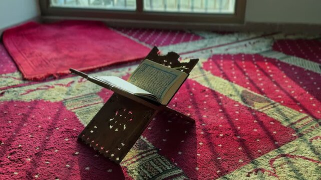 Open Quran placed on a wooden rehal over a prayer mat with sunlight streaming through a window. Symbol of Islamic faith, spirituality, worship, and devotion. Perfect for Ramadan and prayer visuals.