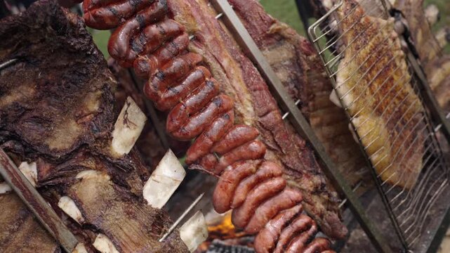 Coiled chorizos glisten as fat slowly renders, behind a costillar &mdash; a whole rib rack &mdash; leans toward the embers, on the side, asado de tira and vac&iacute;o rest on wire grills, absorbing steady warmth.
