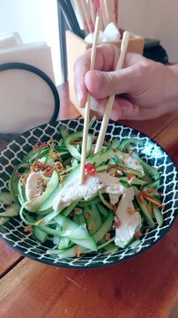 Close up to a plate of thit ga goi tom or traditional Vietnamese chicken cucumber salad with red chili being eaten, candid moment of experiencing local cuisine of Vietnam