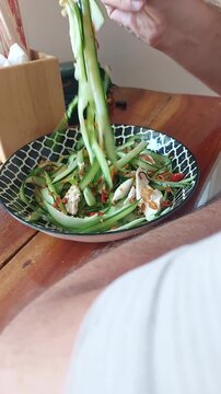 Overhead candid scene of using chopsticks to eat thit ga goi tom or Vietnamese chicken cucumber salad, authentic local dish from Vietnam