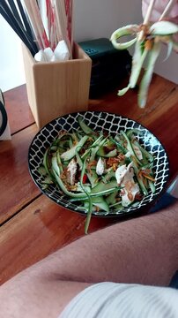 Foodie adding chopped chili to thit ga goi tom or Vietnamese chicken cucumber salad before eating it to add flavor and spice