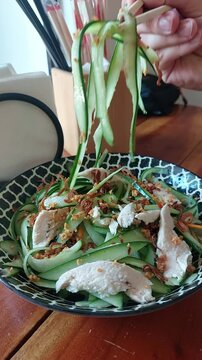 Eating a plate of thit ga goi tom or Vietnamese chicken cucumber salad topped with fried onions, authentic local food from Vietnam