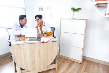 Dedicated Doctors Collaborating on Patient Care Using Laptop in Bright Modern Office