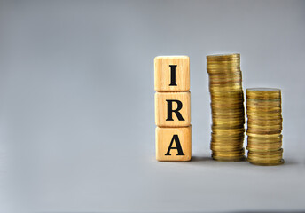 IRA - acronym on wooden cubes on the background of stacks of coins