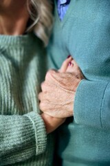 Older Couple Holding Hands in Cozy Green Sweaters, Showing Support and Connection