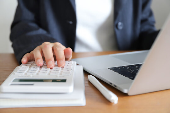 計算機とパソコンを使って働く女性