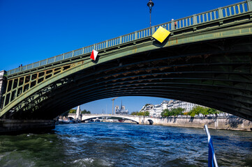 Green Metal Bridge Over Seine River with Notre Dame in Distance