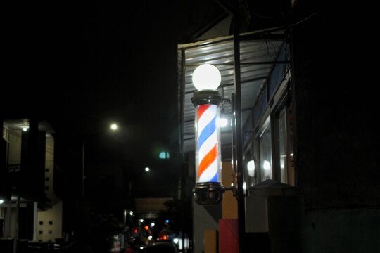 Nighttime Street Scene With Classic Barber Pole Illuminated Outside Shop