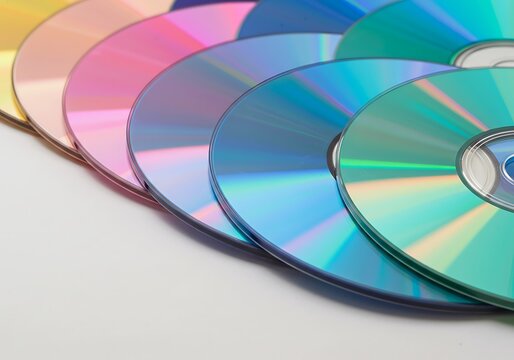 Colorful CDs and DVDs arranged in a fan shape, showcasing their reflective surfaces and vibrant hues.