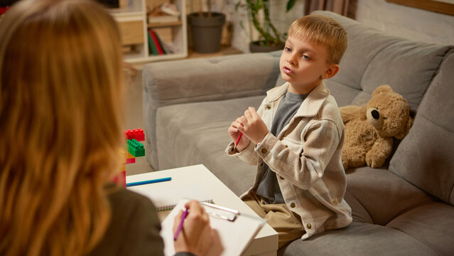 Boy explaining creative idea with toy blocks during psychology counseling session. Concept of communication skill, cognitive development, child education for emotional therapy and healthcare awareness