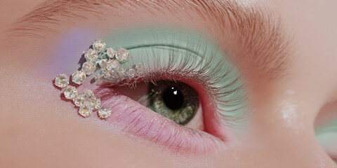 Closeup of a womans eye with creative makeup and sparkling rhinestones Beauty concept of artistic eye makeup, fashion, and glamour