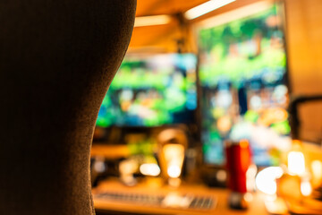 Cozy modern desk setup with warm ambient lighting and green monitor glow, featuring gadgets, keyboard, mic, and gaming chair in a stylish studio workspace. Perfect for background or lifestyle tech the