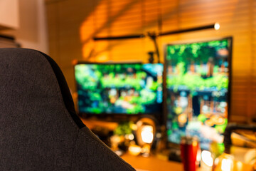 Cozy modern desk setup with warm ambient lighting and green monitor glow, featuring gadgets, keyboard, mic, and gaming chair in a stylish studio workspace. Perfect for background or lifestyle tech the