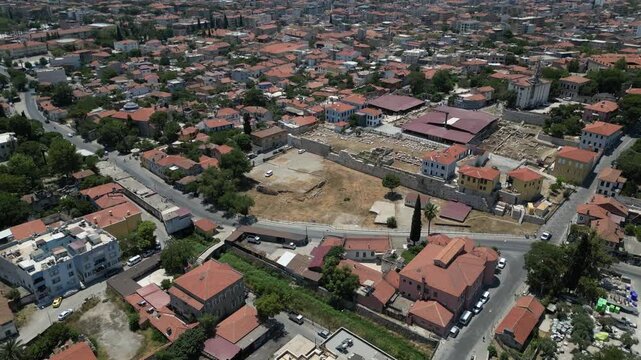 Aerial view of the Baltalı Kapı and city buildings, a tapestry of red-tiled roofs interspersed with lush greenery, Milas, Mugla, Turkey.