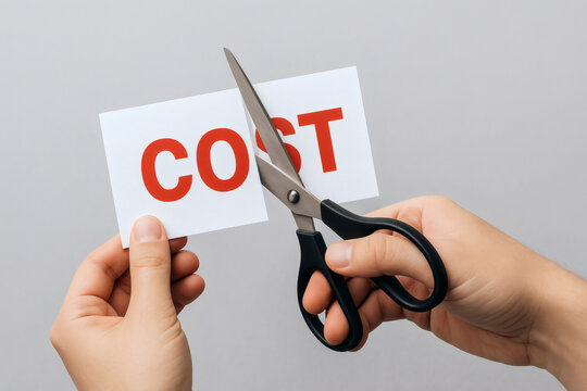 ハサミでCOSTという赤い文字が書かれた紙を切りコスト削減や経費節減を表現するイメージ