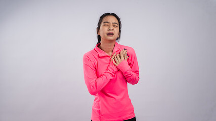 Asian woman in a bright pink long-sleeve sports shirt and black shorts posing against a plain white...