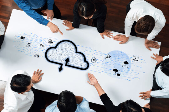 A diverse team collaborates on cloud computing strategies, highlighting digital icons and data flows on an office table, representing teamwork in modern business solutions. Trope