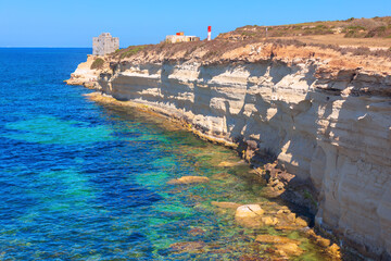 Munxar Path scenic coastal trail in Malta, located near Saint Thomas Bay in Marsaskala. Rugged white limestone cliffs, turquoise water of Mediterranean Sea, and historical watchtower in distance