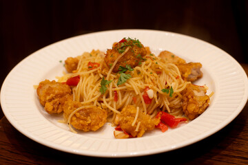 Spicy spaghetti with crispy fried chicken, fresh chili, and holy basil. A delicious Thai-Italian fusion pasta dish. Top-down view.