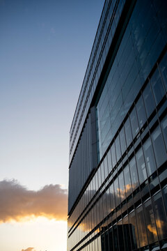 Evening light on glass tower facade of modern architecture, blending geometry, vertical structure, and design harmony across city skyline with subtle reflection and soft atmosphere