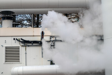 Industrial steam vents release white vapor outdoors