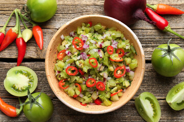 Tasty salsa in bowl and ingredients on wooden table, flat lay