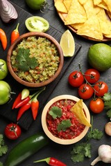 Tasty salsa in bowl and ingredients on black table, flat lay