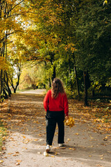 Fototapeta premium Woman in red sweater enjoying autumn park, away from phone and noise.