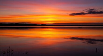 Obraz premium Fiery Sunset Reflection on Calm Lake Water.