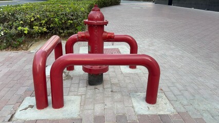 The image shows a fire hydrant painted in bright red, situated on a sidewalk. It features multiple...