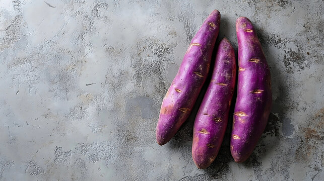 Fresh ube purple sweet potatoes on rustic gray background 