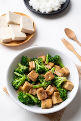 Stir fried tofu and broccoli with soy sauce in bowl on white background, Asian vegan food