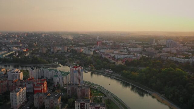Aerial evening view of Orel city in Russia with river, Strelka, main buildings, churches and roads. Beautiful cityscape with lights reflecting on water at sunset, showing urban architecture, skyline.