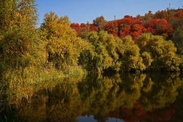 Fototapeta premium Soldier Lake. A lake in a mountainous area with different vegetation. Bright juicy autumn leaves, leaf fall and reflection in the water.